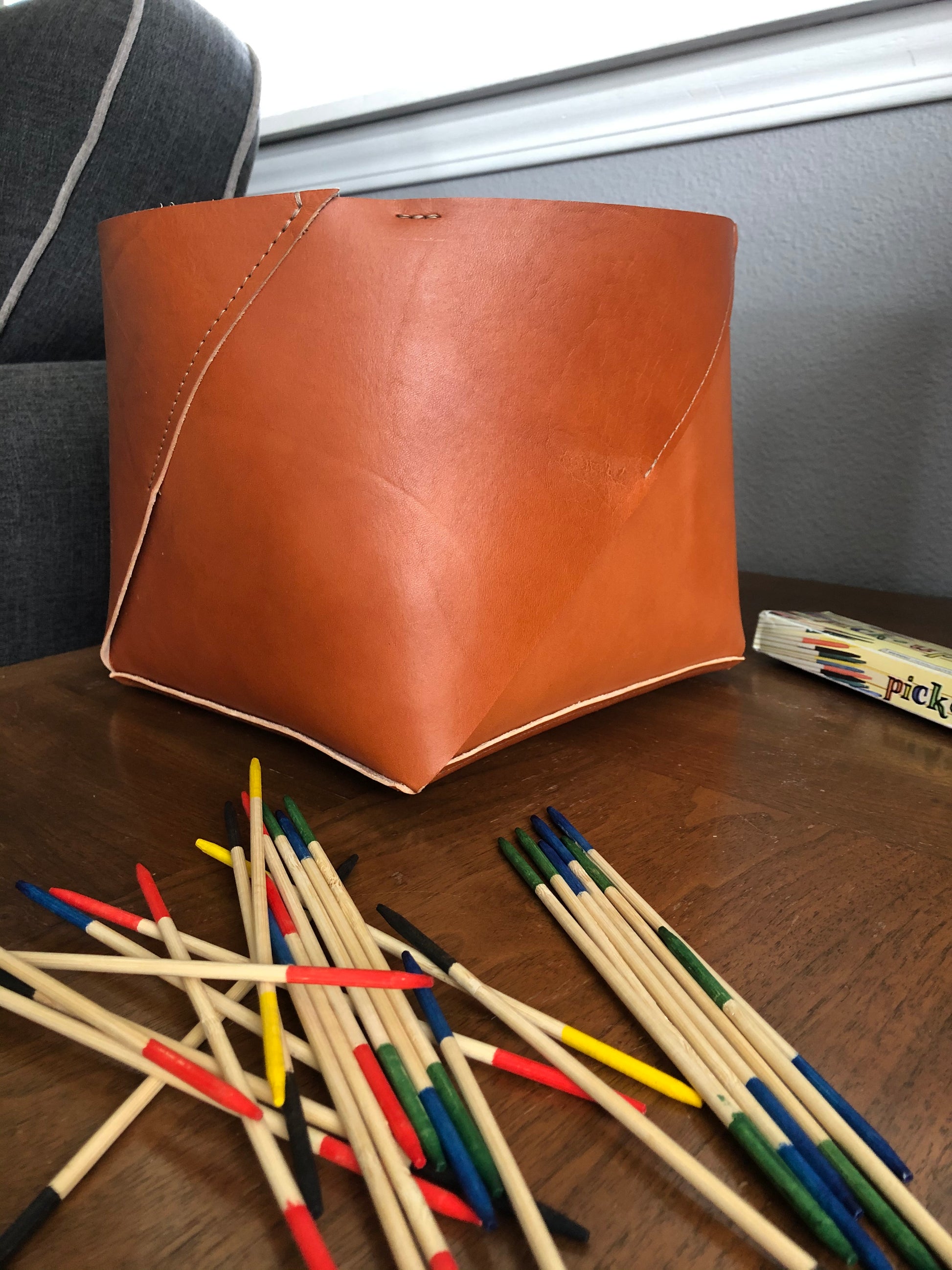 Rich tan leather box sits on end table near a game of Pick Up Sticks