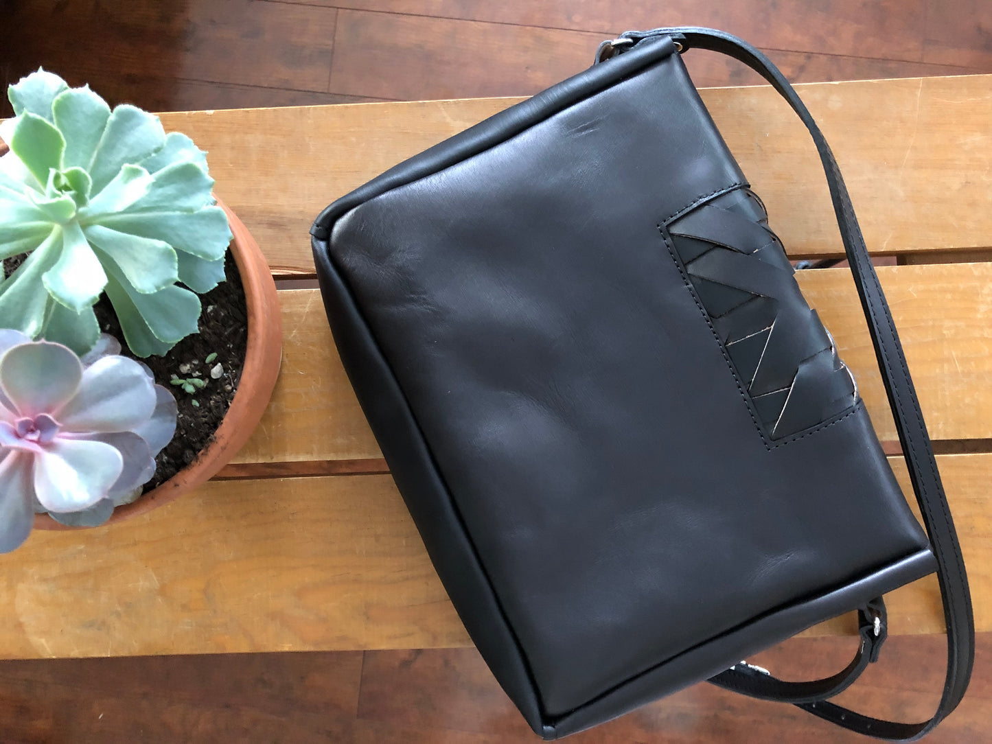 Back view of black leather crossbody bag with woven panel.