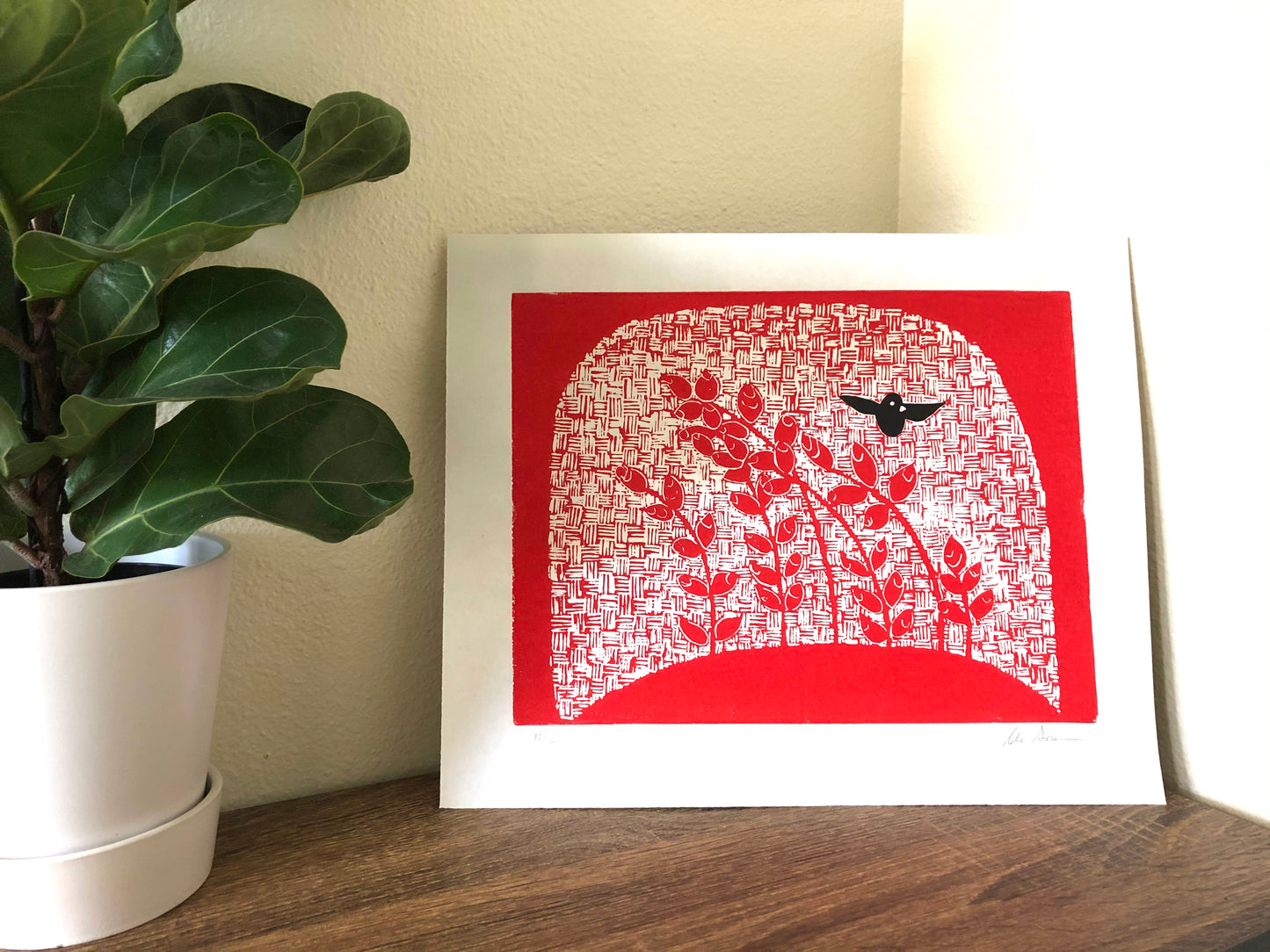 Cheerful blackbird print rests on a table near a potted plant.