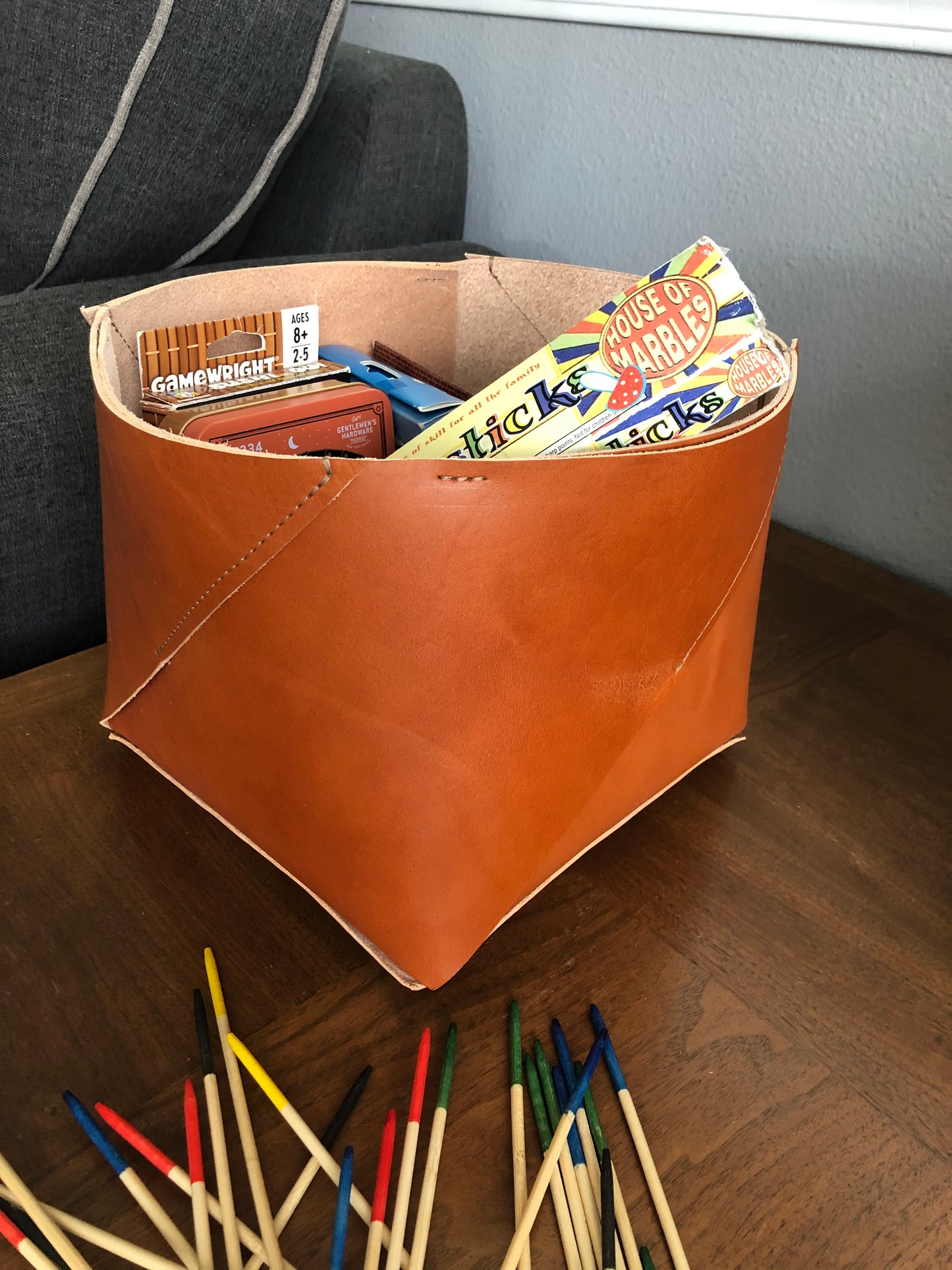 Tan leather bin holds an assortment of games.