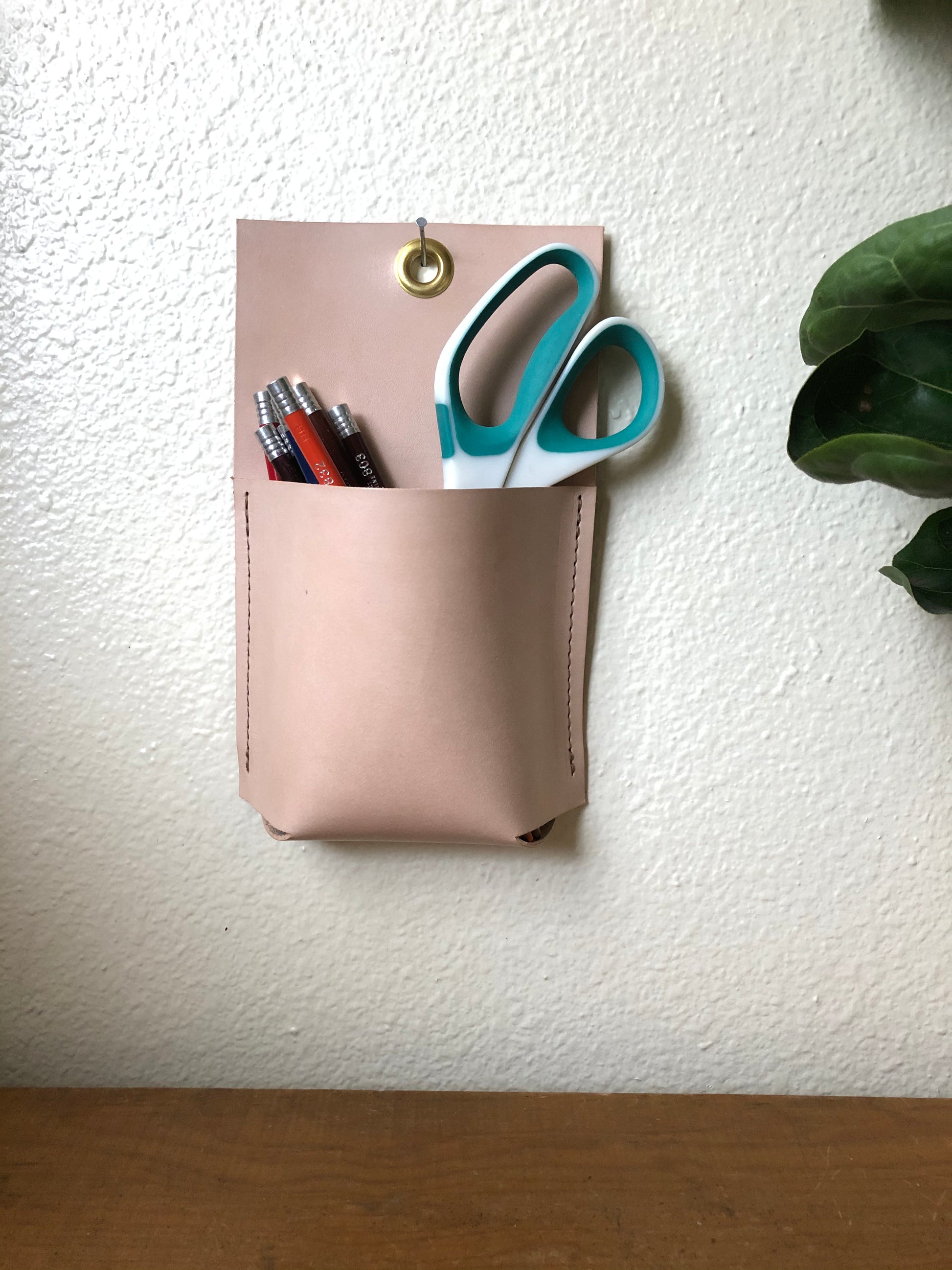 Modern, nude wall pocket holds pencils and scissors.