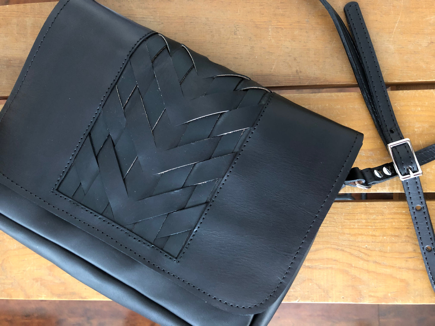 Black leather crossbody bag with woven center panel.