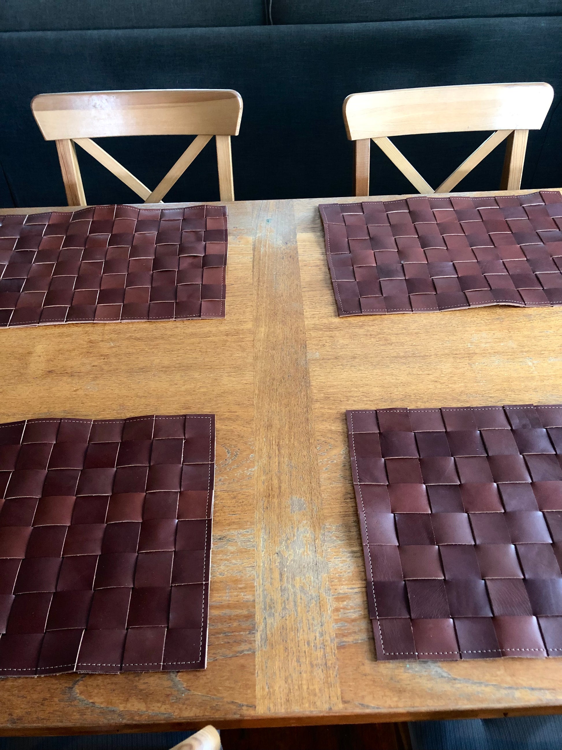 Luxe leather placemats decorate a wooden table.