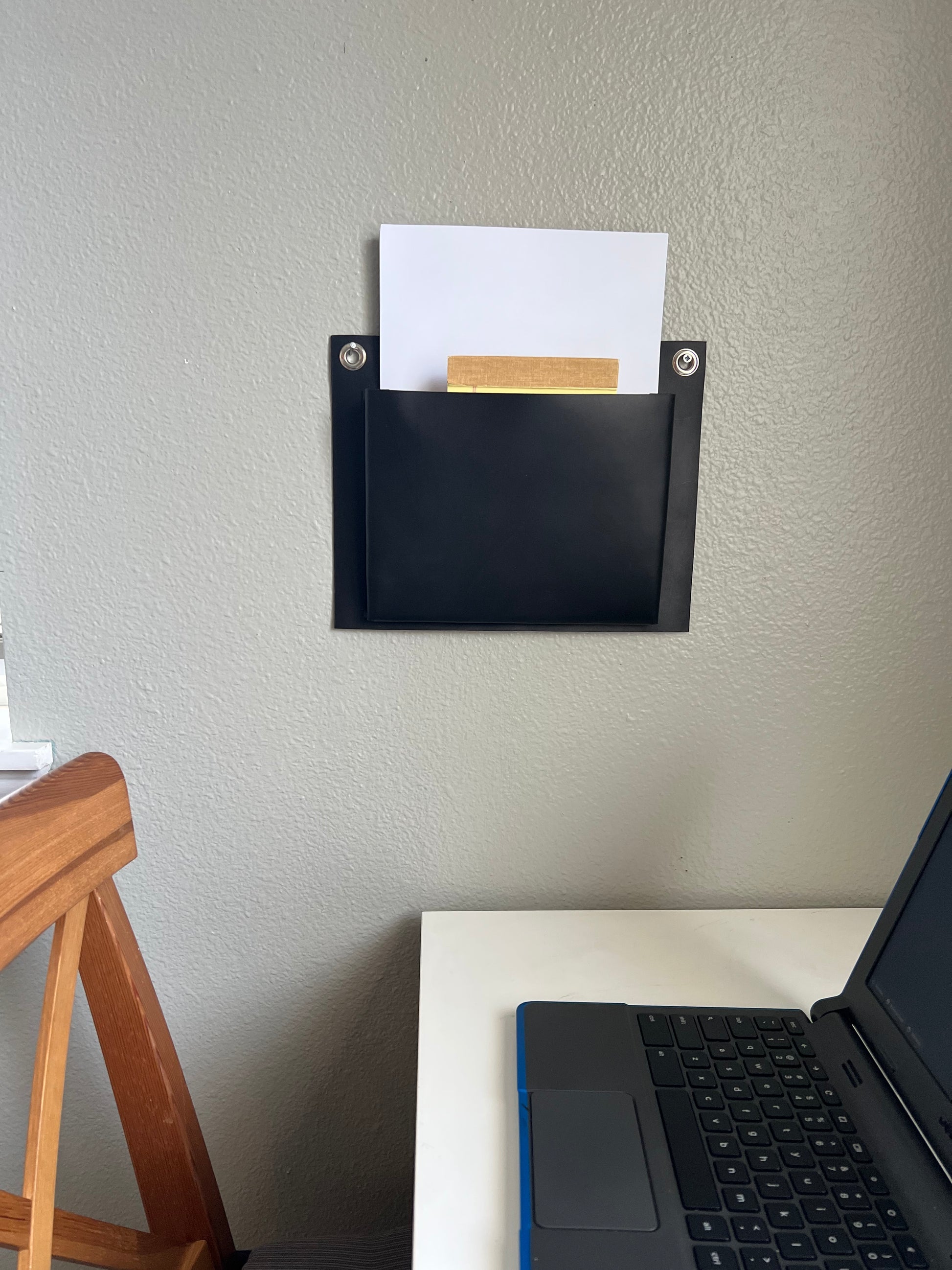 Black leather wall pocket hangs above a clean and simple desk.
