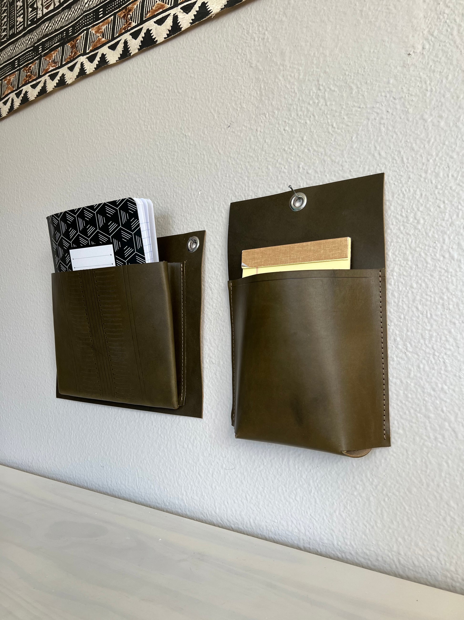 Duo of leather wall pockets holds notebooks in minimal, modern office.