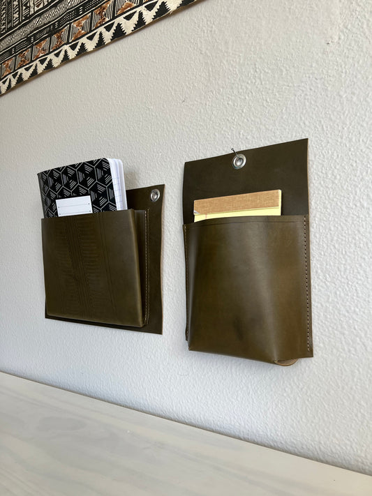 Duo of leather wall pockets holds notebooks in minimal, modern office.