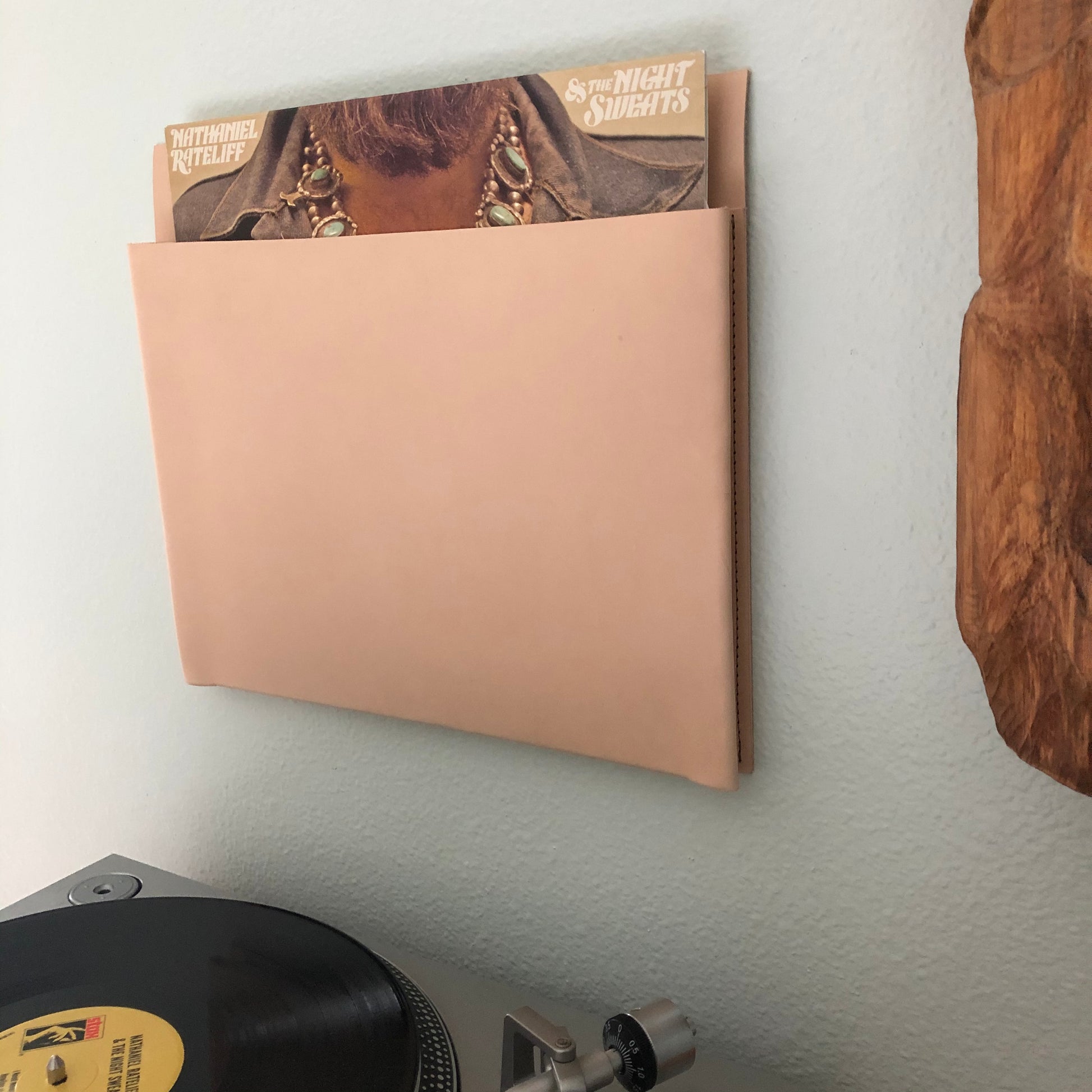 Hanging leather storage pocket displays vinyl record above turntable.