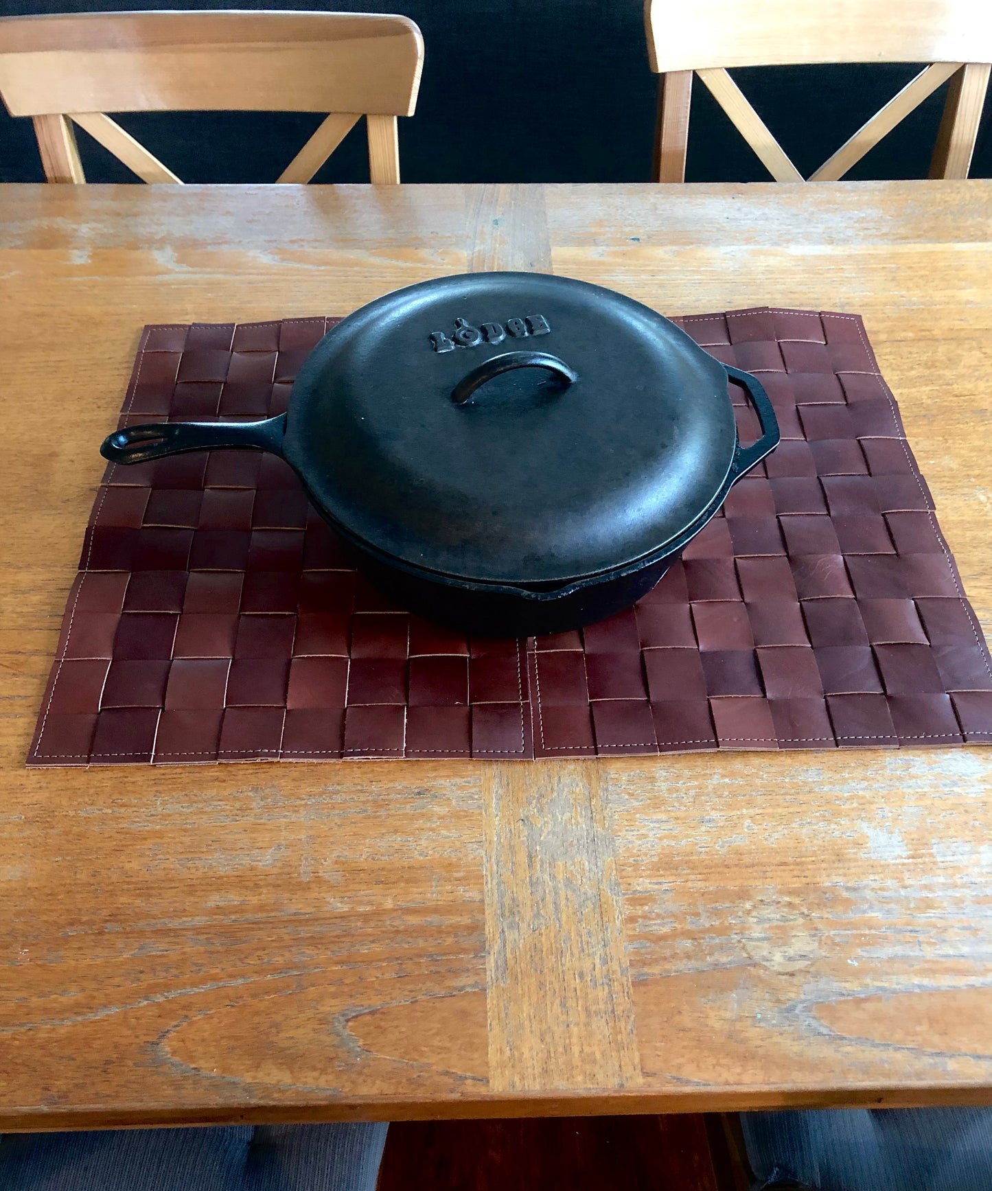 Cast iron skillet rests on woven leather mat.