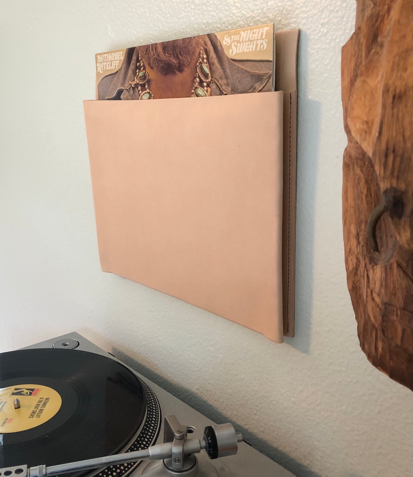 Minimal leather pocket holds vinyl record above turntable.