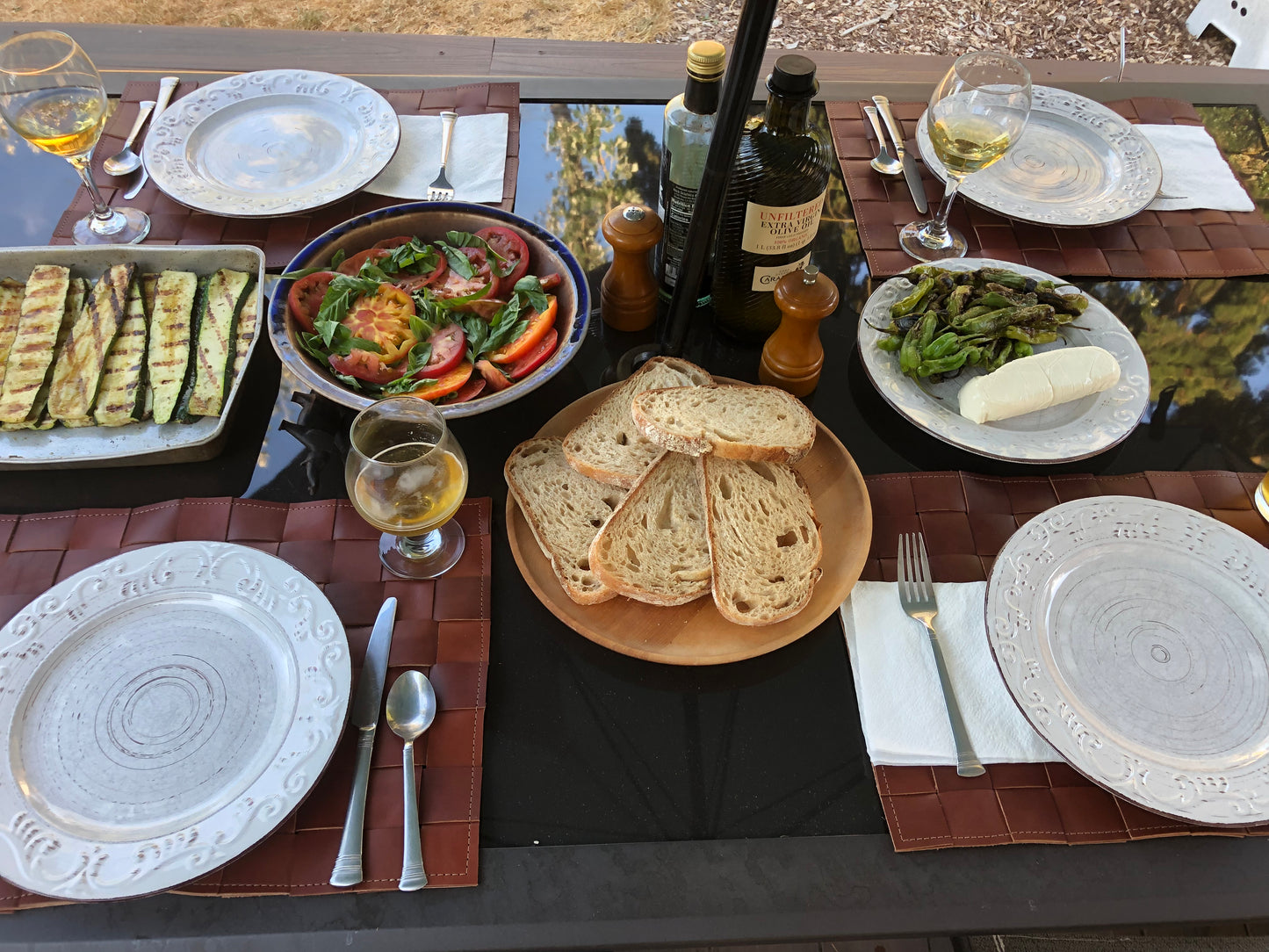 Bountiful outdoor table set with woven leather placemats.