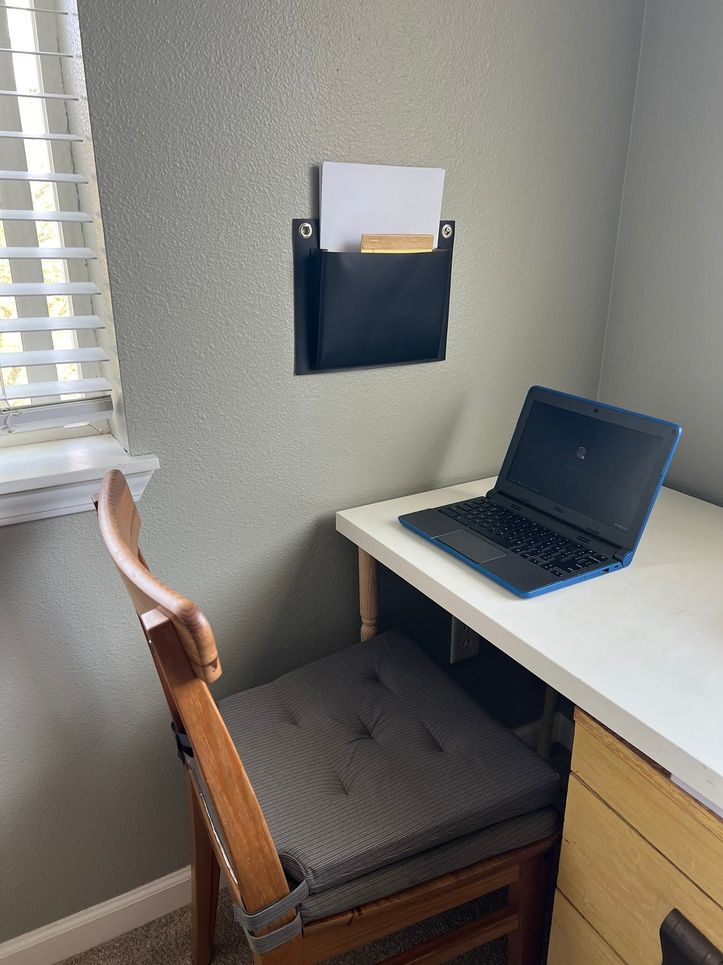 Black leather wall pocket hangs in light, bright home office.