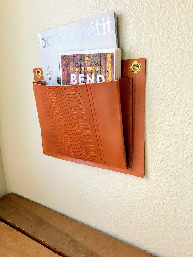 Tan leather wall pocket hangs on wall.