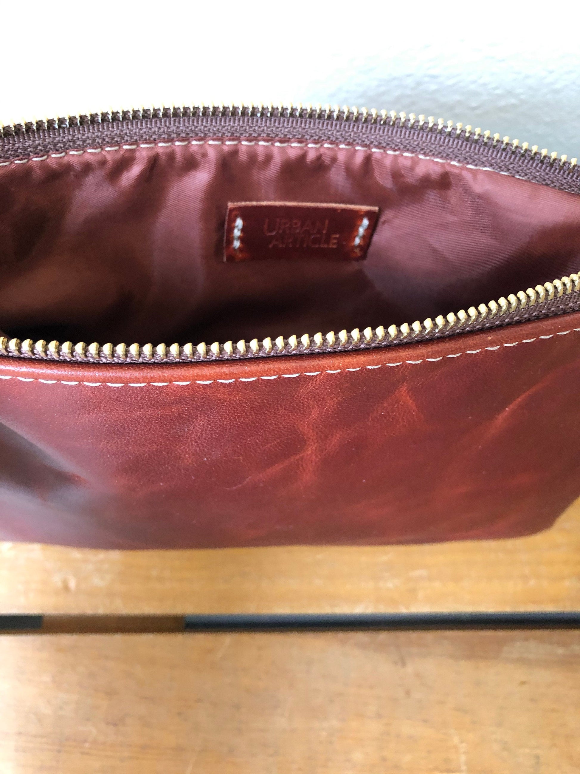 Inside of red brown leather clutch, silky lining and tag also in red brown