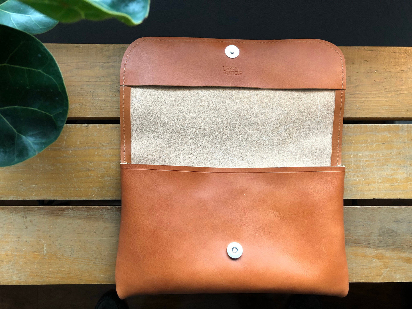 Tan leather clutch opened to see natural leather interior and magnetic clasp
